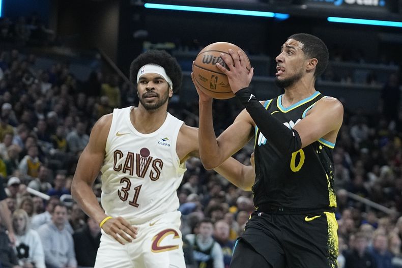 Tyrese Haliburton (0) de los Pacers de Indiana observa para dar un pase ante Jarrett Allen (31) de los Cavaliers de Cleveland durante la 2da mitad del juego de In-Season de la NBA, el viernes 3 de noviembre de 2023, en Indianápolis. (AP Foto/Darron Cummings)