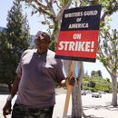 Dee Thompson, miembro del sindicato WGA y SAG-AFTRA, pasa junto a unos árboles árboles recién podados con un cartel en una manifestación frente a los estudios Universal el miércoles 19 de julio de 2023 en Burbank, California. (Foto AP/Chris Pizzello)