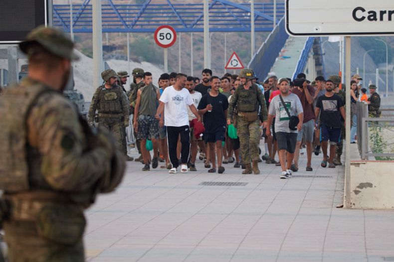 Militares españoles escoltan a migrantes que cruzaron a España de regreso a Marruecos desde el enclave español de Ceuta, el sábado 1 de agosto de 2026. (Foto AP/Antonio Sempere)