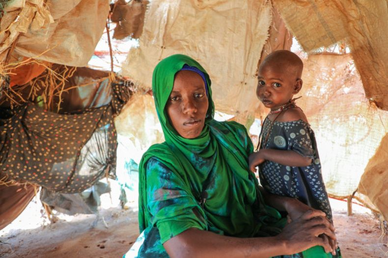 Nurto Madey, una madre desplazada por la sequía, sostiene a su hija dentro de su choza improvisada en el campamento Ladan para personas desplazadas internamente en Dolow, en el sur de Somalia, el miércoles 25 de marzo de 2026. (AP Foto/Mohamed Sheikh Nor)