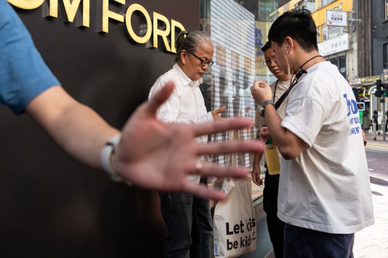 Policías detienen y registran al artista Sanmu Chen en la zona de Causeway Bay la víspera del 37mo aniversario de la represión en la plaza de Tiananmen en Hong Kong, el miércoles 3 de junio de 2026. (AP Foto/Chan Long Hei)