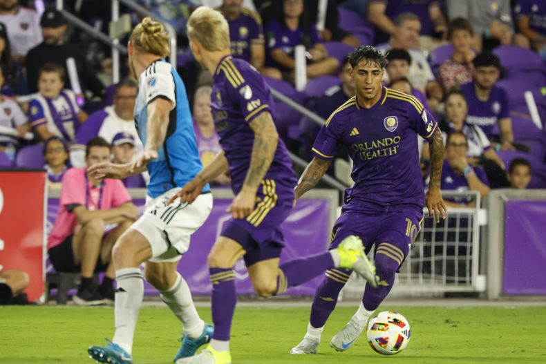 Facundo Torres, derecha, del Orlando City, conduce el balón durante la primera mitad, mientras su compañero Dagur Dan Þórhallsson, es marcado por Tim Ream, izquierda, del Charlotte FC, durante el primer tiempo del primero partido al mejor de tres de la serie de primera ronda de la Copa MLS, el domingo 27 de octubre de 2024, en Orlando, Florida. (AP Foto/Kevin Kolczynski)