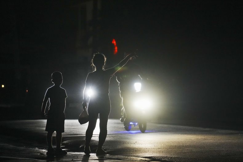 Una mujer y un niño a la espera de conseguir un transporte durante el apagón programado de electricidad en Bauta, Cuba, el lunes 18 de marzo de 2024. La isla enfrenta una crisis de energía, con varios apagones en las últimas semanas. (AP Foto/Ramón Espinosa)