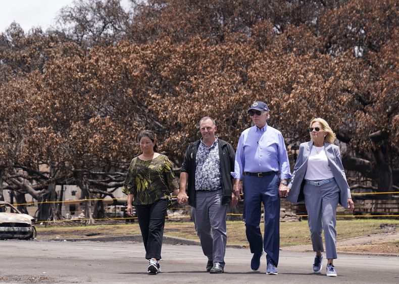 ARCHIVO - El presidente Joe Biden y la primera dama Jill Biden caminan con el gobernador de Hawai Josh Green, segundo por la izquierda, y su esposa Jaime Green mientras pasan por el enorme árbol Banyan durante su visita a las zonas devastadas por los incendios forestales de Maui, el 21 de agosto de 2023, en Lahaina, Hawai. (AP Foto/Evan Vucci, Archivo)