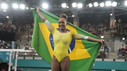 La brasileña Rebeca Andrade se arropa con su bandera nacional tras ganar la medalla de oro en el salto con potro de los Juegos Panamericanos en Santiago, Chile, el martes 24 de octubre de 2023. (AP Foto/Martín Mejía)