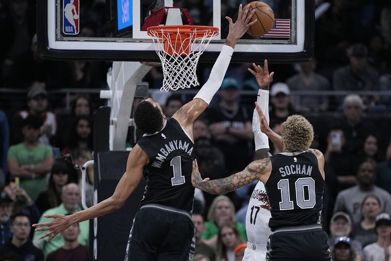 Victor Wembanyama (1), de los Spurs de San Antonio, bloquea un tiro de Dennis Schroder (17), de los Nets de Brooklyn, durante el tiempo extra del partido de baloncesto de la NBA, en Austin, Texas, el domingo 17 de marzo de 2024. (AP Foto/Eric Gay)