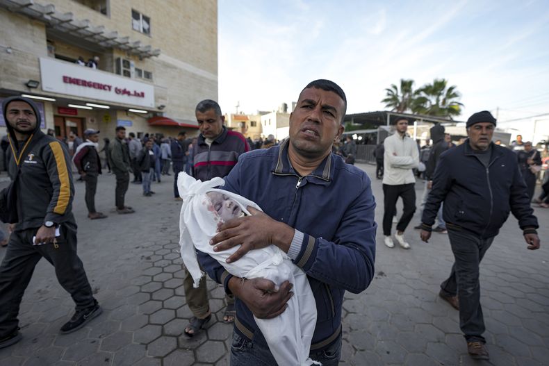 Un hombre reacciona mientras lleva el cuerpo de un niño asesinado por un bombardeo israelí en la Franja de Gaza en el Hospital de Al Aqsa en Deir al Balah, el martes 14 de enero de 2025. (AP Foto/Abdel Kareem Hana)