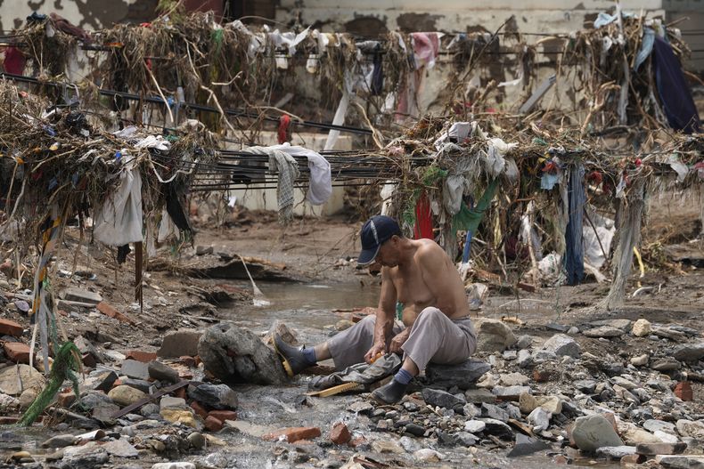 Un hombre lava su ropa en un riachuelo cerca de los restos dejados por una inundación que arrasó la aldea de Nanxinfang, a las afueras de Beijing, el 4 de agosto de 2023. (AP Foto/Ng Han Guan)