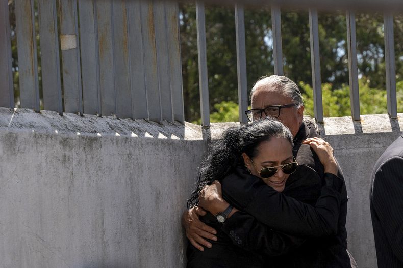 Lorena Villavicencio, hermana del candidato presidencial asesinado Fernando Villavicencio, abraza a su esposo a las afueras de la morgue donde reposaba el cuerpo de su hermano, en Quito, Ecuador, el jueves 10 de agosto de 2023. Villavicencio fue asesinado a tiros a la salida de un acto electoral en un colegio de la capital ecuatoriana, a menos de los semanas de las elecciones presidenciales del 20 de agosto. (AP Foto/Carlos Noriega)