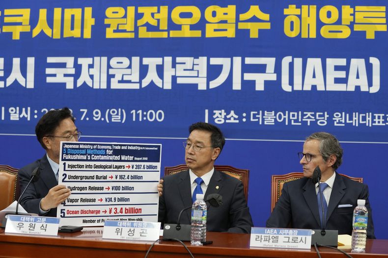 El parlamentario surcoreano Woo Won-shik, del opositor Partido Democrático, a la izquierda, muestra una lista de métodos propuestos para gestionar las aguas contaminadas de la central de Fukushima, ante la mirada de su compañero de partido Wi Seong-gon y de Rafael Mariano Grossi, director general del Organismo Internacional de la Energía Eléctrica, a la derecha, durante una reunión con legisladores del partido en la Asamblea Nacional en Seúl, Corea del Sur, Del domingo 9 de julio de 2023. (AP Foto/Ahn Young-joon)