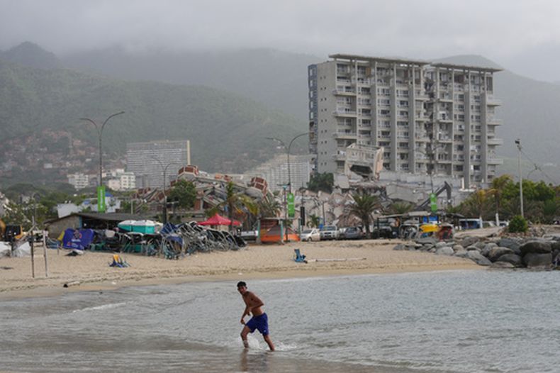 Un hombre sale del mar frente a edificios dañados por sismos en La Guaira, Venezuela, el jueves 2 de julio de 2026. (Foto AP/Matias Delacroix)