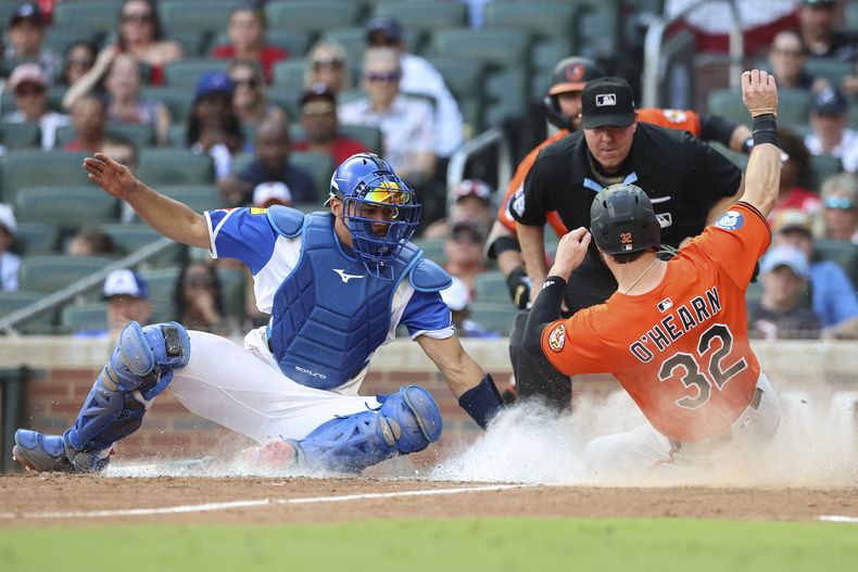 Ryan OHearn, de los Orioles de Baltimore, anota frente a Drake Baldwin, cátcher de los Bravos de Atlanta (AP Foto/Colin Hubbard)