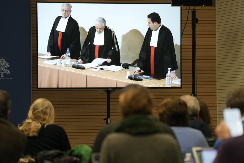 ARCHIVO - En esta foto de archivo del 16 de diciembre de 2023, periodistas miran una pantalla en la sala de prensa del Vaticano en la que el presidente del tribunal, Giuseppe Pignatone, lee el veredicto del juicio al cardenal Angelo Becciu y otros ocho acusados. Varios abogados prominentes han publicado críticas académicas y opiniones legales lapidarias sobre el reciente “juicio del siglo” en el Vaticano en las que destacan violaciones de derechos básicos de la defensa y de normas del estado de derecho que, advierten, podrían tener consecuencias para la Santa Sede en lo sucesivo. (AP Foto/Andrew Medichini, file)