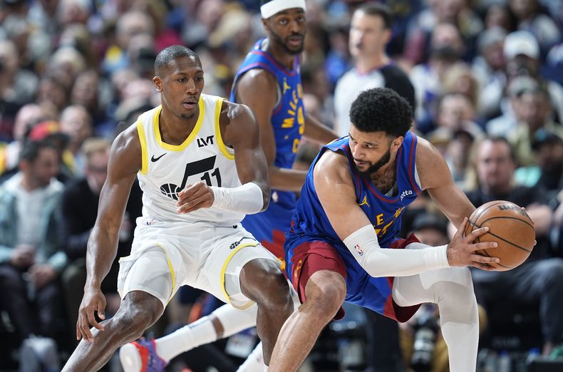 El escolta de los Nuggets de Denver , Jamal Murray, a la derecha, busca pasar el balón mientras el escolta del Jazz de Utah, Kris Dunn, defiende durante la segunda mitad del partido de baloncesto de la NBA, el sábado 9 de marzo de 2024, en Denver. (AP Foto/David Zalubowski)