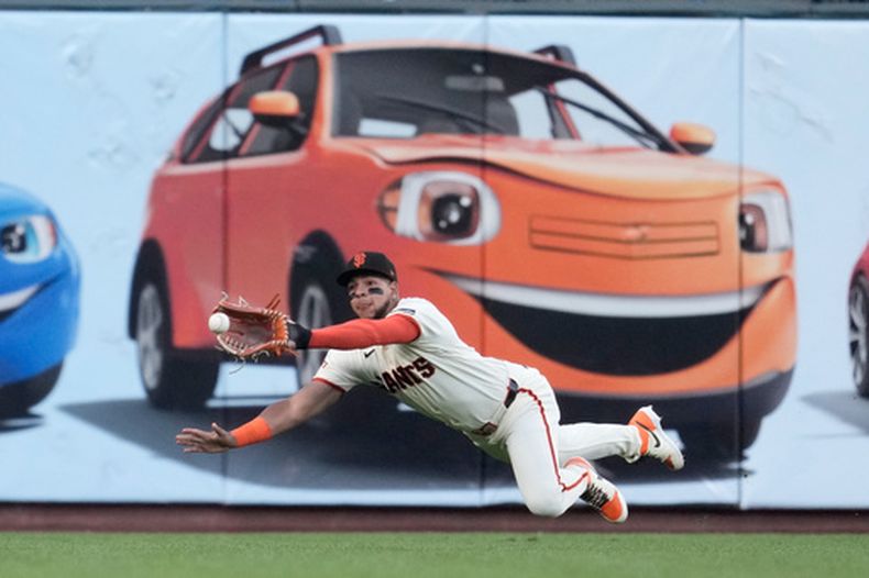 El jardinero izquierdo de los Gigantes de San Francisco, Victor Bericoto, se zambulle para atrapar un elevado bateado por Cole Carrigg, de los Rockies de Colorado, durante la primera entrada de un partido de béisbol, el jueves 9 de julio de 2026, en San Francisco. (Foto AP/Jeff Chiu)