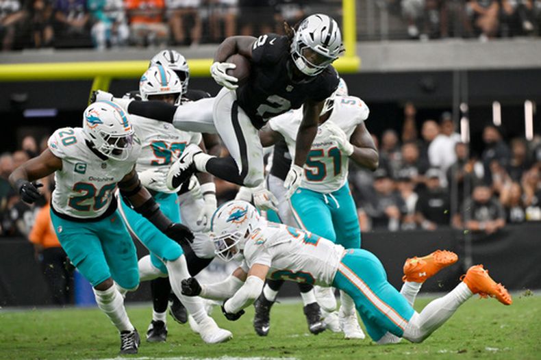 Ashton Jeanty (2), corredor de los Raiders de Las Vegas, brinca sobre Jordyn Brooks (20), de los Dolphins de Miami y escapa de Zayne Anderson (23) durante la segunda mitad del partido de la NFL, el domingo 13 de septiembre de 2026, en Las Vegas. (AP Foto/David Becker)