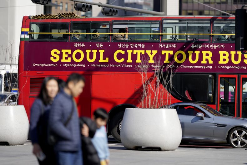 Gente camina cerca un autobús turístico en la capital surcoreana, en Seúl, Corea del Sur, el jueves 27 de febrero de 2025. (AP Foto/Lee Jin-man)