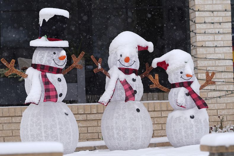 Una capa de nieve fresca cubre tres figuras con forma de muñeco de nieve en el exterior de una vivienda durante una tormenta invernal, el 7 de enero de 2025, en Denver. (AP Foto/David Zalubowski)