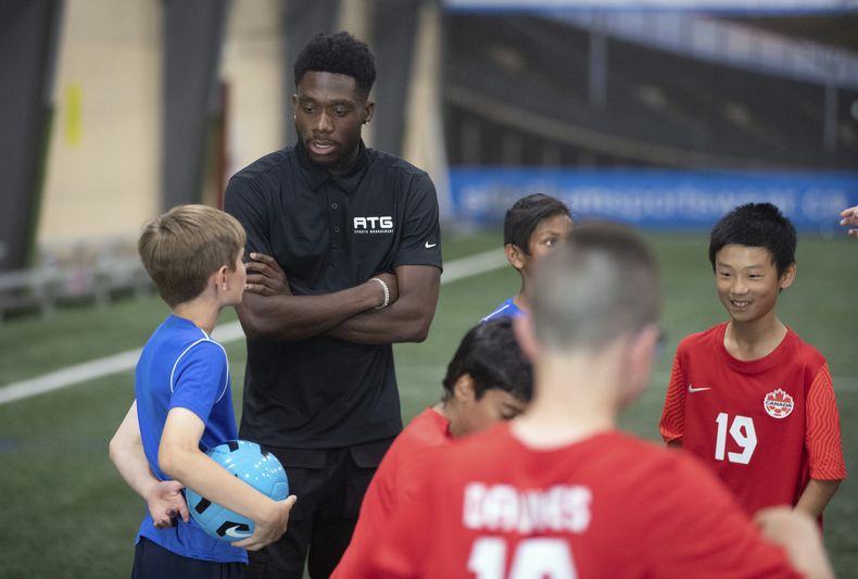Alphonso Davies, de la selección canadiense, habla con niños durante un campamento en Edmonton, el martes 6 de junio de 2023 (Jason Franson/The Canadian Press via AP)