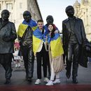 Aficionados colocan una bandera de Ucrania a una estatua en homenaje a los Beatles, antes de Eurovisión, en Liverpool, Inglaterra, el 12 de mayo de 2023. (Aaron Chown/PA via AP)