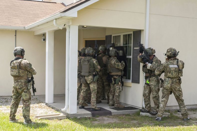 Miembros de un equipo de respuesta especial del Servicio de Control de Inmigración y Aduanas (ICE) muestran cómo entran a una vivienda para dar con una persona buscada, en el centro de formación federal en Brunswick, Georgia, el 21 de agosto de 2025. (AP Foto/Fran Ruchalski)