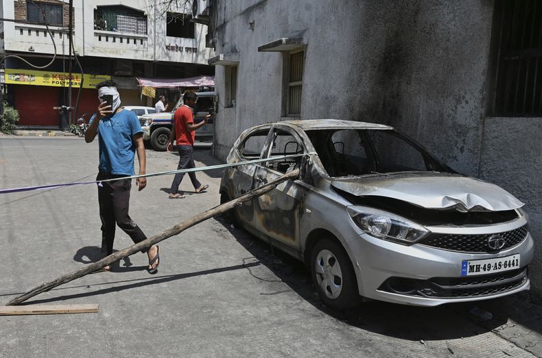 Una persona toma fotos de un vehículo quemado en la víspera tras disturbios provocados por protestas para la demolición de la tumba del gobernante musulmán mongol del siglo XVII Aurangzeb, en Nagpur, India, el 18 de marzo de 2025. (AP Foto)
