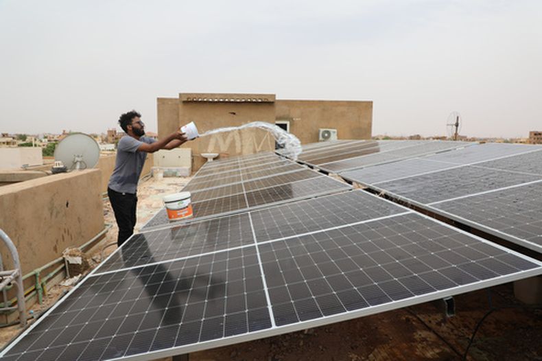 Un técnico limpia paneles solares instalados en el tejado de una vivienda en Omdurmán, en las afueras de Jartum, Sudán, el 23 de julio de 2026. (Foto AP/Mohnd Blal)
