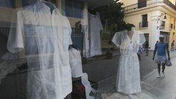 Camisas y vestidos de guayabera se exhiben a la venta en un escaparate en La Habana, Cuba, el domingo 26 de mayo de 2024. La guayabera fue creada en el siglo XVIII para los trabajadores agrícolas y con el tiempo se ha convertido en prenda formal y símbolo de Cuba. (Foto AP/Ariel Ley)