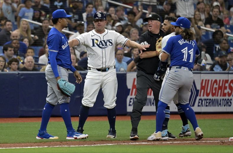 El coach de tercera base de los Rays de Tampa Bay, Brady Williams (centro a la izquierda), el umpire Corey Blaser y el campocorto de los Azulejos de Toronto Bo Bichette (11) intentan interrumpir una confrontación entre José Caballero (segundo a la derecha) de Tampa Bay y el relevista de los Azulejos de Toronto Génesis Cabrera (izquierda), a la izquierda, durante la séptima entrada, el sábado 30 de marzo de 2024, en San Petersburgo, Florida. (AP Foto/Steve Nesius)