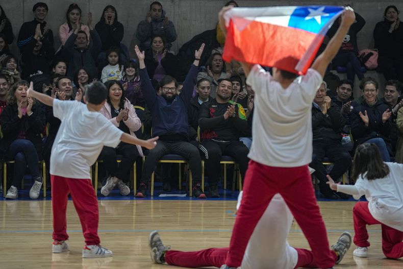 El presidente de Chile Gabriel Boric levanta los brazos mientras observa a los bailarines de breakdance durante la ceremonia para el conteo a 100 días de los Juegos Panamericanos en el centro deportivo la Pintana en Santiago, Chile el miércoles 12 de julio del 2023. (AP Foto/Esteban Felix)