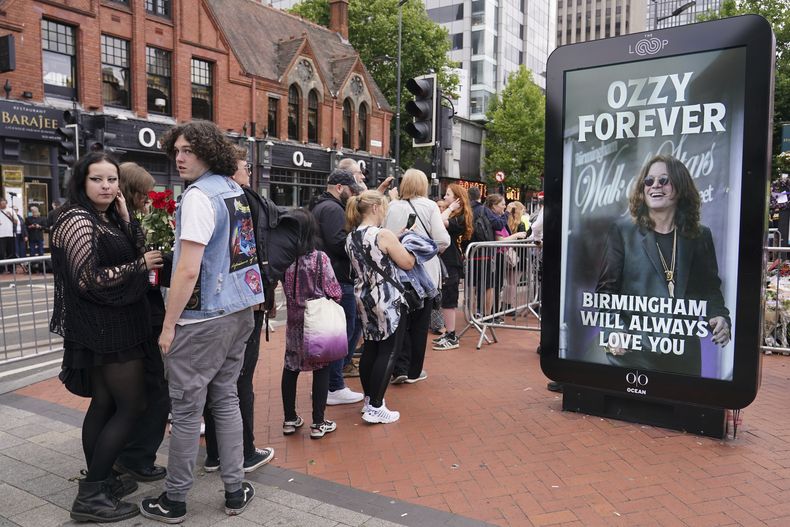 Fans hacen fila para ver y colocar ofrendas para el músico Ozzy Osbourne, cuando miles de fans se reunieron para ver una procesión fúnebre por el líder de Black Sabbath, Ozzy Osbourne, luego de su muerte a los 76 años, en Birmingham, Inglaterra, el miércoles 30 de julio de 2025. (Foto AP/Alberto Pezzali)