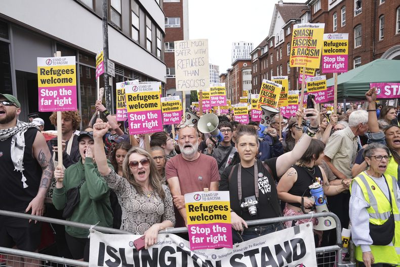 Manifestantes de la campaña Stand Up To Racism se congregan frente al Hotel Thistle City Barbican, en el centro de Londres, que alberga a solicitantes de asilo, el sábado 2 de agosto de 2025. (PA vía AP)