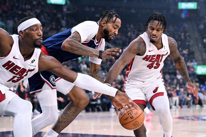 Bam Adebayo (13), del Heat de Miami, y su compañero de equipo Davion Mitchell (45) disputan el balón con Derrick Jones Jr., centro, de los Clippers de Los Ángeles, durante la primera mitad del juego de baloncesto de la NBA, el lunes 3 de noviembre de 2025, en Los Ángeles. (AP Foto/Wally Skalij)