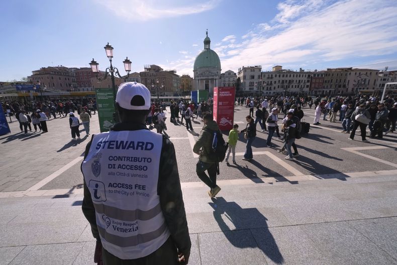 Varios empleados revisan los códigos QR de los visitantes fuera de la principal estación de trenes de Venecia, Italia, el viernes 18 de abril de 2025. La ciudad cobrará un impuesto de llegada a los viajeros de un día por segundo año consecutivo. (AP Foto/Antonio Calanni)