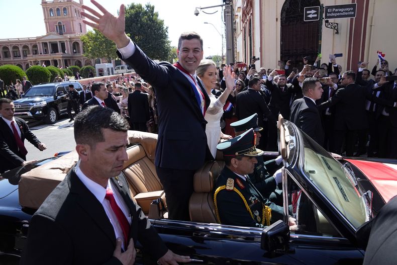 El nuevo presidente de Paraguay, Santiago Peña, y su esposa, Leticia Ocampos, saludan desde un automóvil mientras se dirigen a la Catedral el día de la asunción de Peña en Asunción, Paraguay, el martes 15 de agosto de 2023. (AP Foto/Jorge Saenz)