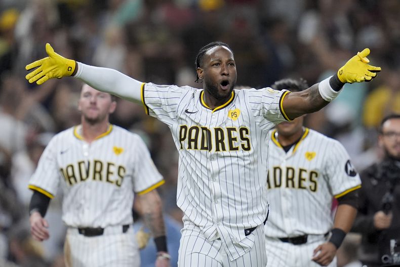 Jurickson Profar, centro, de los Padres de San Diego, celebra después de batear sencillo productor de dos carreras para vencer a los Nacionales de Washington durante la décima entrada del juego de béisbol el lunes 24 de junio de 2024, en San Diego. Los Padres ganaron 7-6. (AP Foto/Gregory Bull)