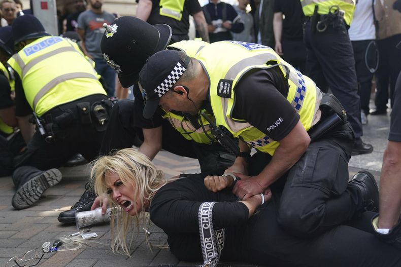 Agentes de policía detienen a una mujer durante una protesta en Nottingham, en la plaza Englands Market, el sábado 3 de agosto de 2024, tras un ataque con arma blanca el lunes en Southport en el que murieron tres niñas. (Jacob King/PA via AP)