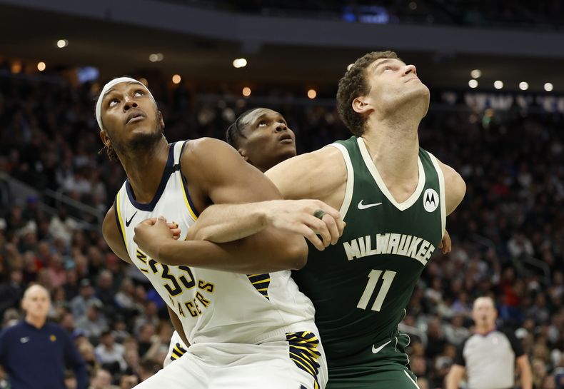 Myles Turner (33), de los Pacers de Indiana, batalla por la posición con Brook Lopez, de los Bucks de Milwaukee, buscando un rebote en la segunda mitad del juego de baloncesto de la NBA, el lunes 1 de enero de 2024, en Milwaukee. (AP Foto/Jeffrey Phelps)