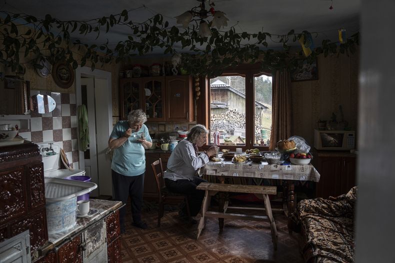 Ivan y Maria Zelechuk comen en su cocina antes de visitar una iglesia para la celebración navideña en la aldea de Kryvorivnia, Ucrania, el lunes 25 de diciembre de 2023. (Foto AP/Evgeniy Maloletka)