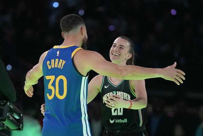 Stephen Curry, de los Warriors de Golden State, abraza a Sabrina Ionescu, del Liberty de Nueva York, tras el duelo de triples que ambos disputaron el sábado 17 de febrero de 2024 en Indianápolis (AP Foto/Darron Cummings)