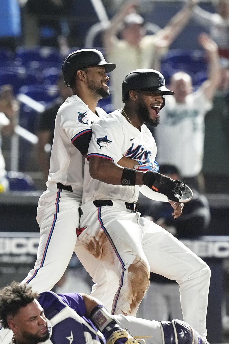 Otto López, de los Marlins de Miami, carga al dominicano Bryan de la Cruz, quien anotó la carrera del triunfo sobre los Rockies de Colorado, el martes 30 de abril de 2024 (AP Foto/Marta Lavandier)