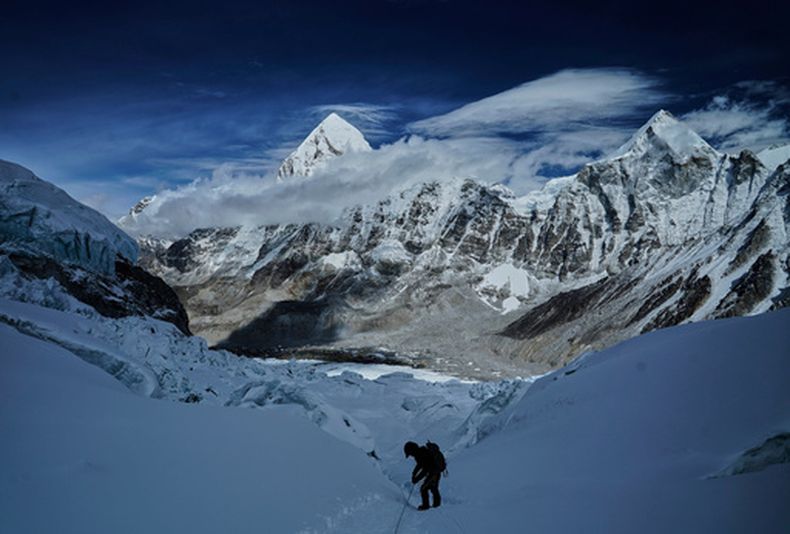 ARCHIVO - El monte Pumori (centro, izquierda), de fondo mientras un montañero avanza por la cascada de hielo Khumbu para descencer al campo base del Everest, en Nepal, el 4 de mayo de 2025. (AP Foto/Pasang Rinzee Sherpa, archivo)