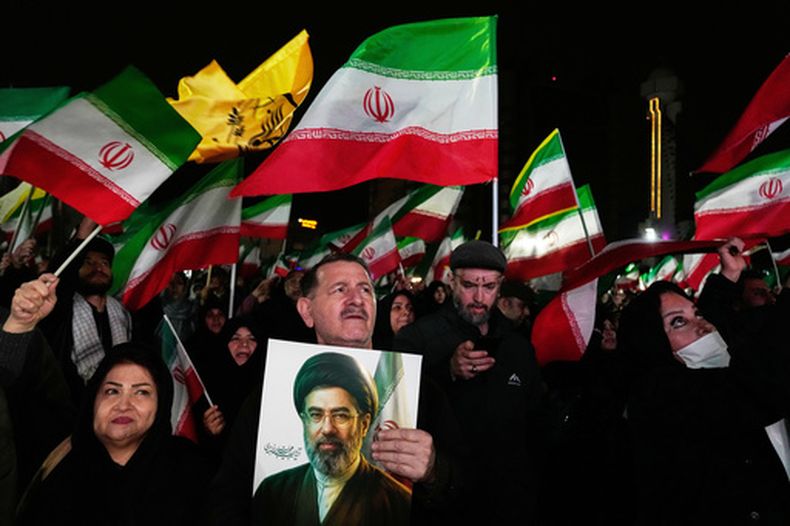 Manifestantes progubernamentales ondean banderas iraníes mientras uno sostiene una imagen del líder supremo, el ayatolá Mojtaba Jamenei, durante un acto en una plaza en el oeste de Teherán, Irán, el 25 de marzo de 2026. (AP Foto/Vahid Salemi)