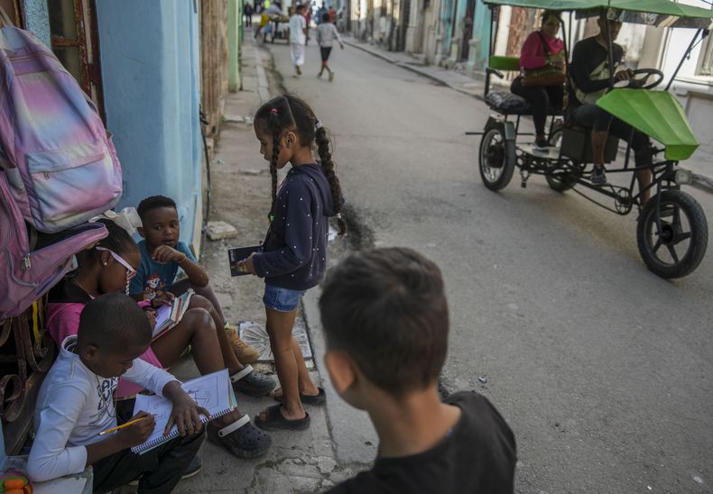 Los niños hacen su tarea en la puerta de una casa durante un apagón en La Habana, Cuba, el miércoles 4 de diciembre de 2024. (AP Foto/Ramón Espinosa)