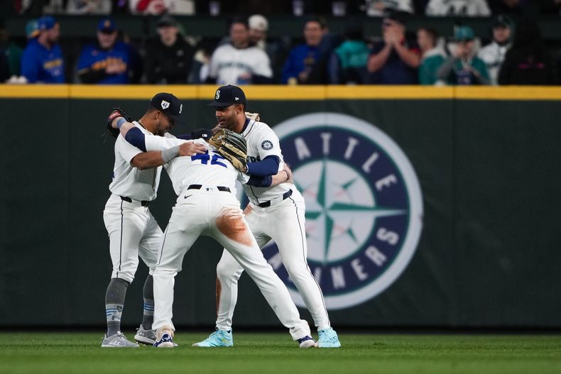 El jardinero izquierdo de los Marineros de Seattle, Jonatan Clase, a la izquierda, el jardinero derecho Luke Raley, el centro, y el jardinero central Julio Rodríguez, a la derecha, celebran una victoria por 9-3 sobre los Rojos de Cincinnati en un juego de béisbol el lunes 15 de abril de 2024, en Seattle. (AP Foto/Lindsey Wasson)