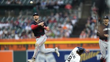 Kyle Farmer (12), segunda base de los Mellizos de Minnesota, lanza para completar un doble play mientras que Matt Vierling (8), de los Tigres de Detroit, se barre en segunda, en la sexta entrada del juego de béisbol, el viernes 23 de junio de 2023, en Detroit. (AP Foto/Paul Sancya)