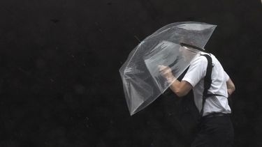 Una persona sostiene un paraguas contra el fuerte viento y la lluvia mientras camina por una calle de Tokio el viernes 2 de junio de 2023. (Foto AP/Eugene Hoshiko)