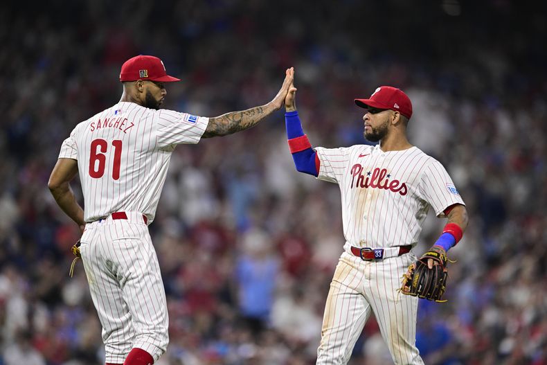 Cristopher Sánchez (61), de los Filis de Filadelfia, choca los cinco con Edmundo Sosa después de que Sosa completara una doble matanza contra los Nacionales de Washington durante la octava entrada el sábado 17 de agosto de 2024, en Filadelfia. (AP Foto/Derik Hamilton)