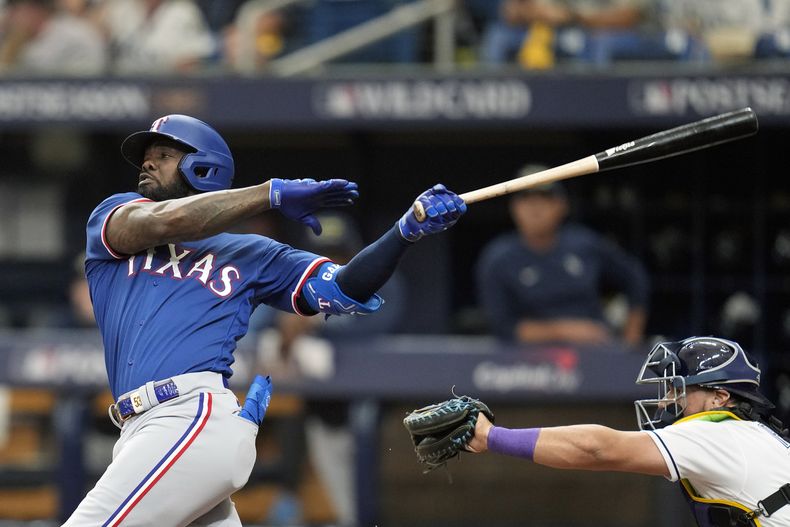 ARCHIVO - Adolis García (izquierda) de los Rangers de Texas batea contra los Rays de Tampa Bay en el primer juego de la serie de comodines de los playoffs, el 3 de octubre de 2023. (AP Foto/John Raoux)