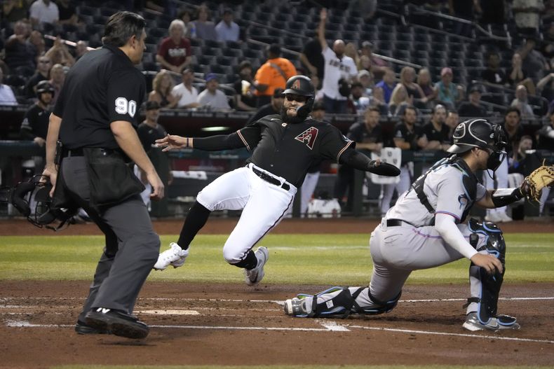 Emmanuel Rivera de los Diamondbacks de Arizona anota frente al cátcher de los Marlins de Miami Nick Fortes tras un doble de Christian Walker en la cuarta entrada del juego del lunes 8 de mayo del 2023. (AP Foto/Rick Scuteri)